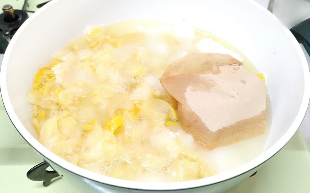 柚子ジャム果汁・皮・薄皮・砂糖・水・種を鍋に入れて煮ている写真